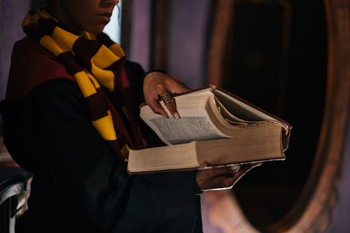 A Woman in Black Robe and with a Scarf Holding a Book