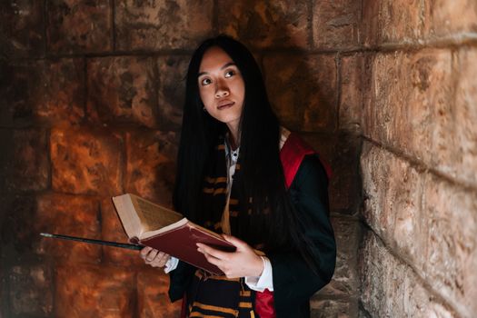 A woman in a wizard costume holding a spellbook, evoking a magical atmosphere.