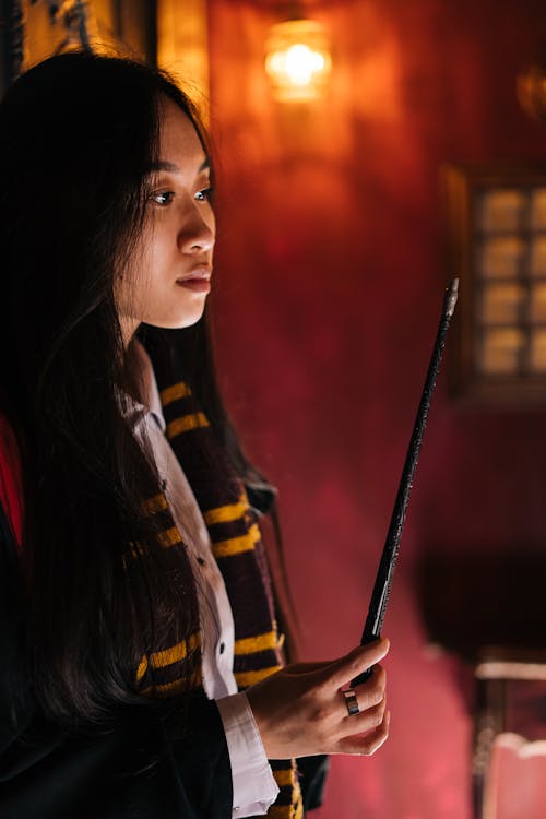 A Woman in Black Robe and Scarf Holding a Wand