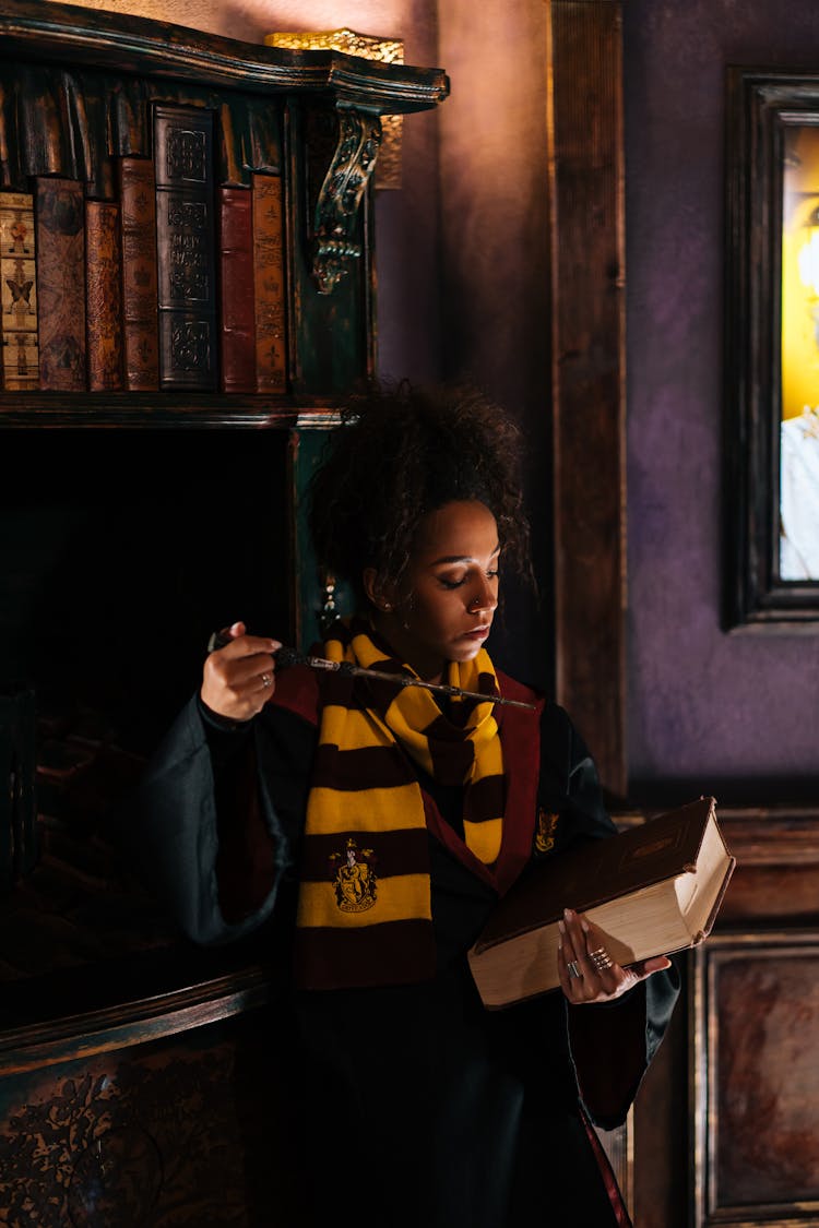 A Woman In Black Robe And Scarf Holding A Wand