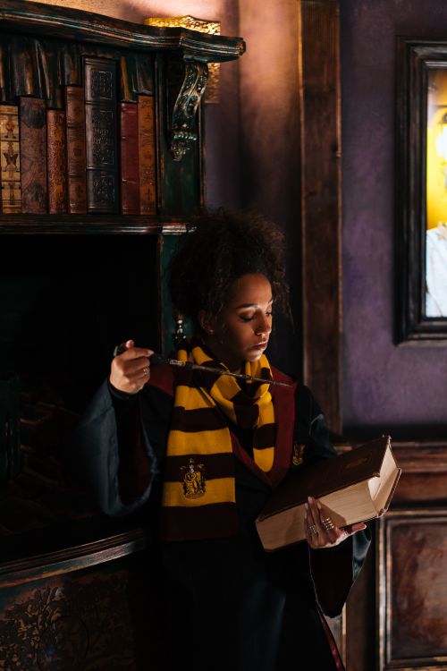Free A woman in a wizard costume reading a book indoors, evoking fantasy themes. Stock Photo
