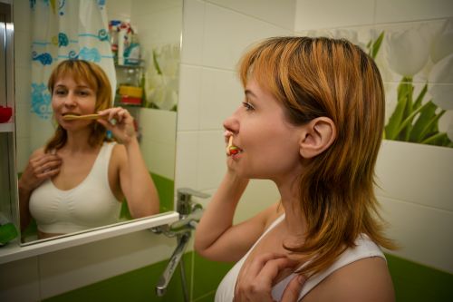 Free Redhead woman brushes teeth in bright bathroom, focusing on dental hygiene. Stock Photo