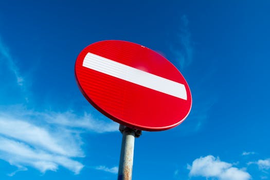Close-up of a red do not enter sign against a clear blue sky with clouds.