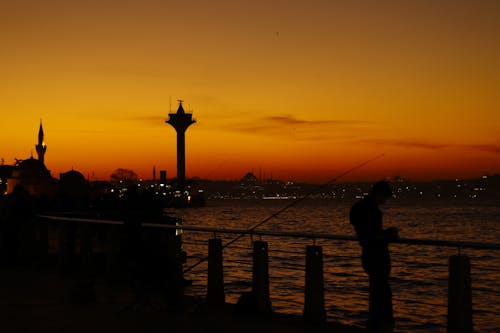 Silhouette of Man Standing on Bridge During Sunset