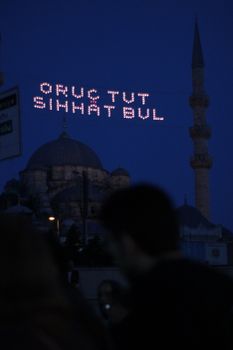 An evening view of a mosque with illuminated text against a dark sky.