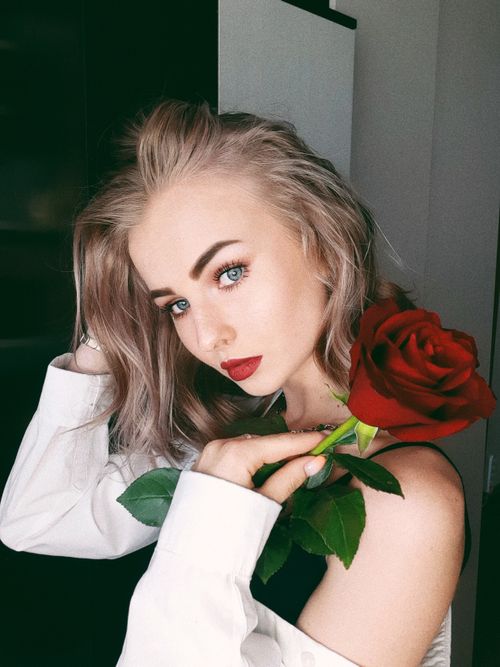 Free Woman posing with a red rose, exuding elegance and beauty. Stock Photo