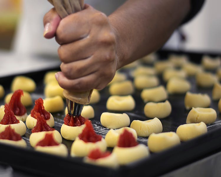 A Baker Squeezing Fillings From A Piping Bag