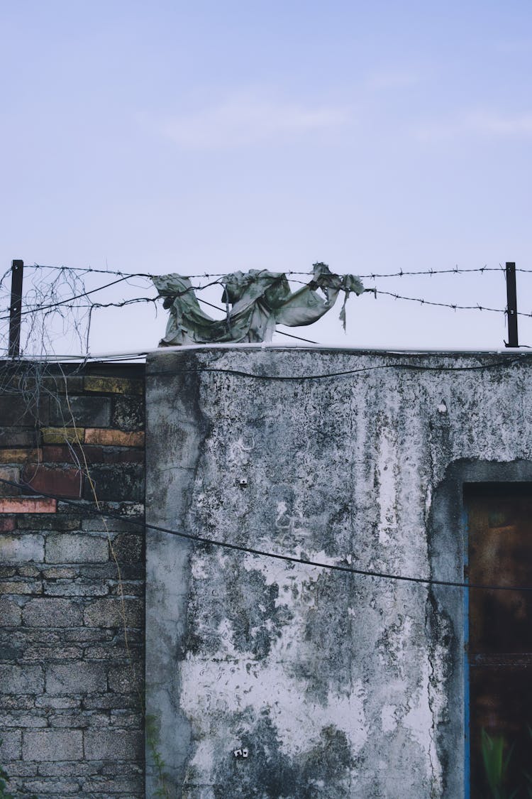 Barbed Wire On Top Of A Weathered Concrete Wall