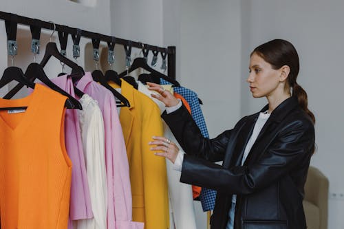 Woman in Black Leather Jacket  Standing Near Clothing Rack