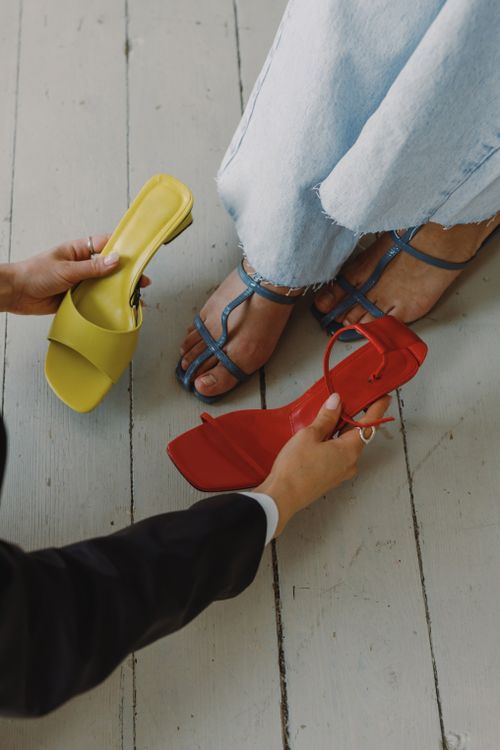 Free Fashionable footwear selection with hands helping choose shoes on wooden floor. Stock Photo