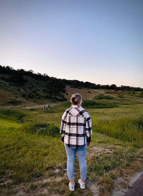 Free Woman in Plaid Shirt Standing on Grass Field Stock Photo