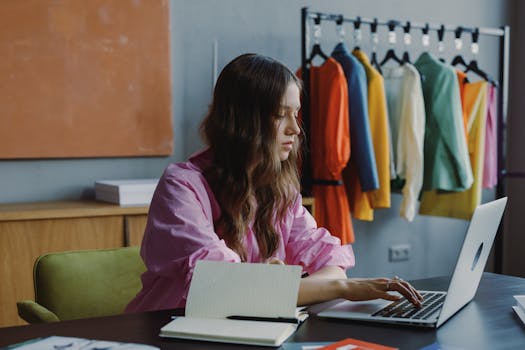 Professional woman working at desk with laptop in fashion studio office space.