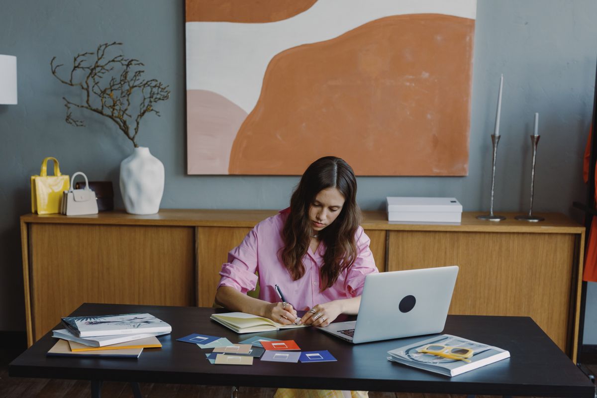 Person working from a home desk beside a laptop and notebook — photo by Ron Lach on Pexels