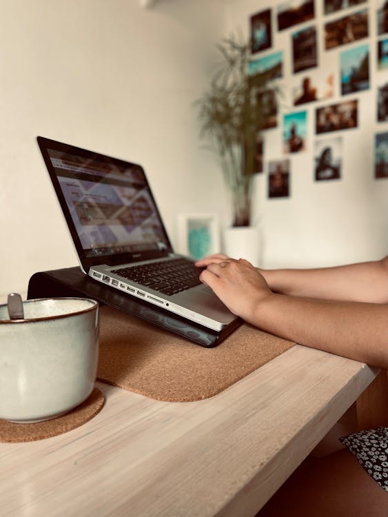 Free Person Using Laptop on Brown Wooden Table Stock Photo