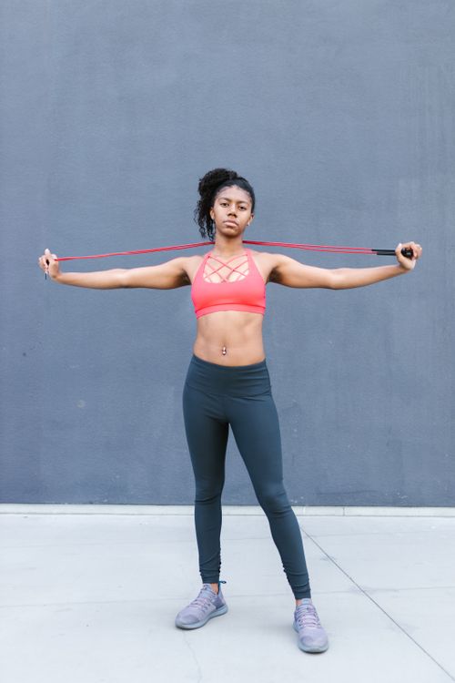 Free Strong woman in sports attire posing with a jump rope against a modern backdrop. Stock Photo