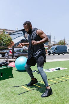 Athletic man practicing agility ladder drills on green lawn during outdoor workout.