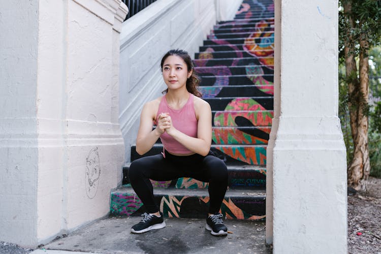 Woman Squatting Beside The Stairs