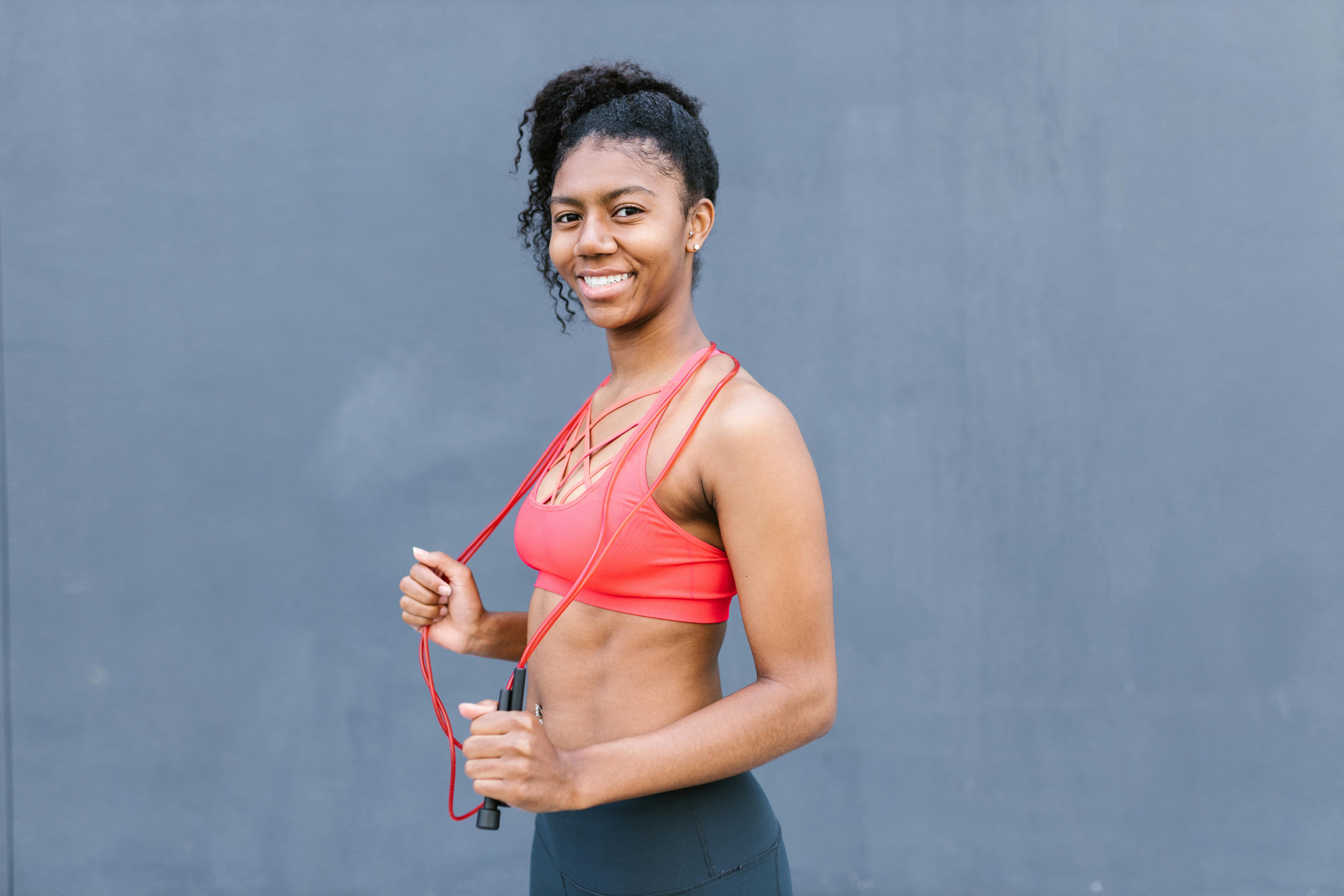 Woman Wearing Red Sports Bra Holding Skipping Ropes Smiling · Free Stock  Photo