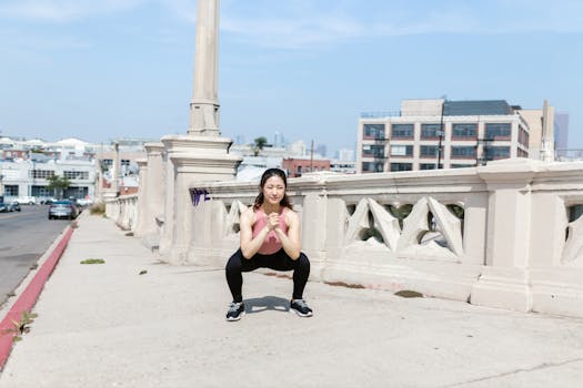 Woman exercising outdoors, performing squats on a city sidewalk.