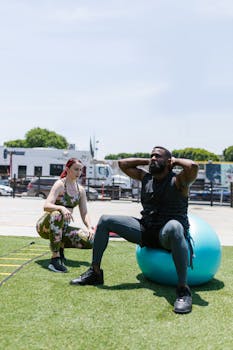 Two people engaged in a fitness workout outdoors using an exercise ball.