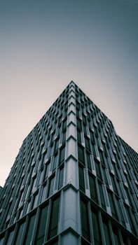 Low angle view of a contemporary high-rise building with geometric design against a clear sky.
