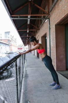 Side view of a fit woman doing calisthenics on a building balcony.