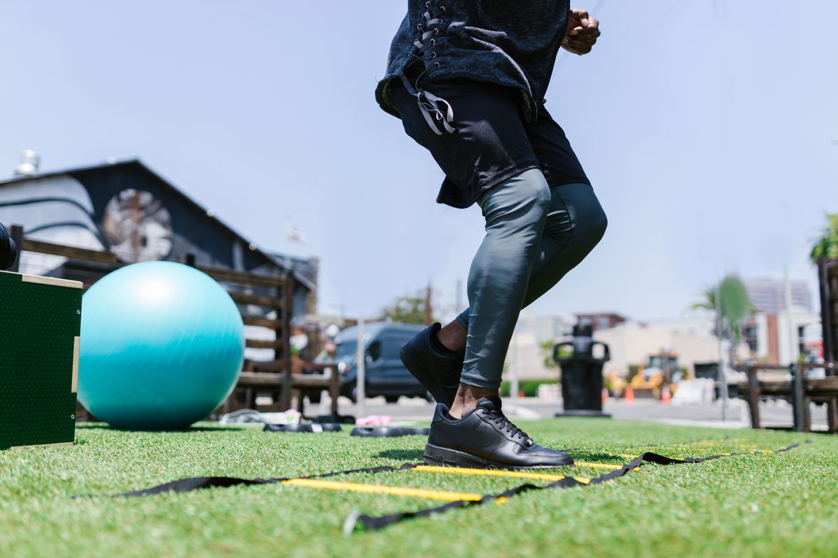 Athlete training with an agility ladder and fitness equipment outdoors