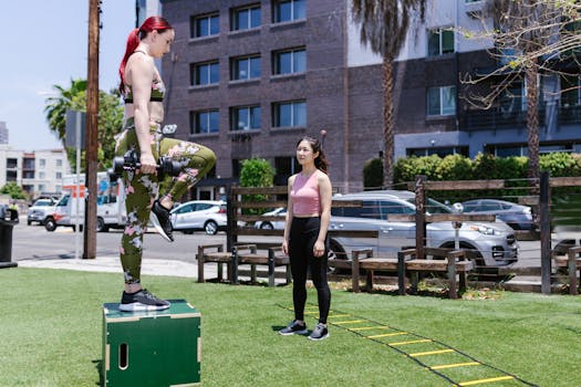 Two women practicing step-up exercises outdoors with fitness equipment.