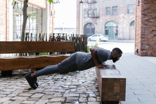 Fit man doing push-ups on a bench in an urban outdoor setting, focusing on fitness and healthy lifestyle.