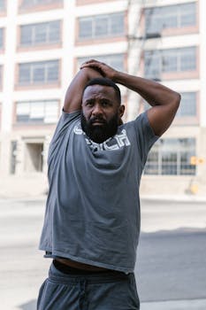 A fit man stretching his arms in an urban setting, embracing a healthy lifestyle.