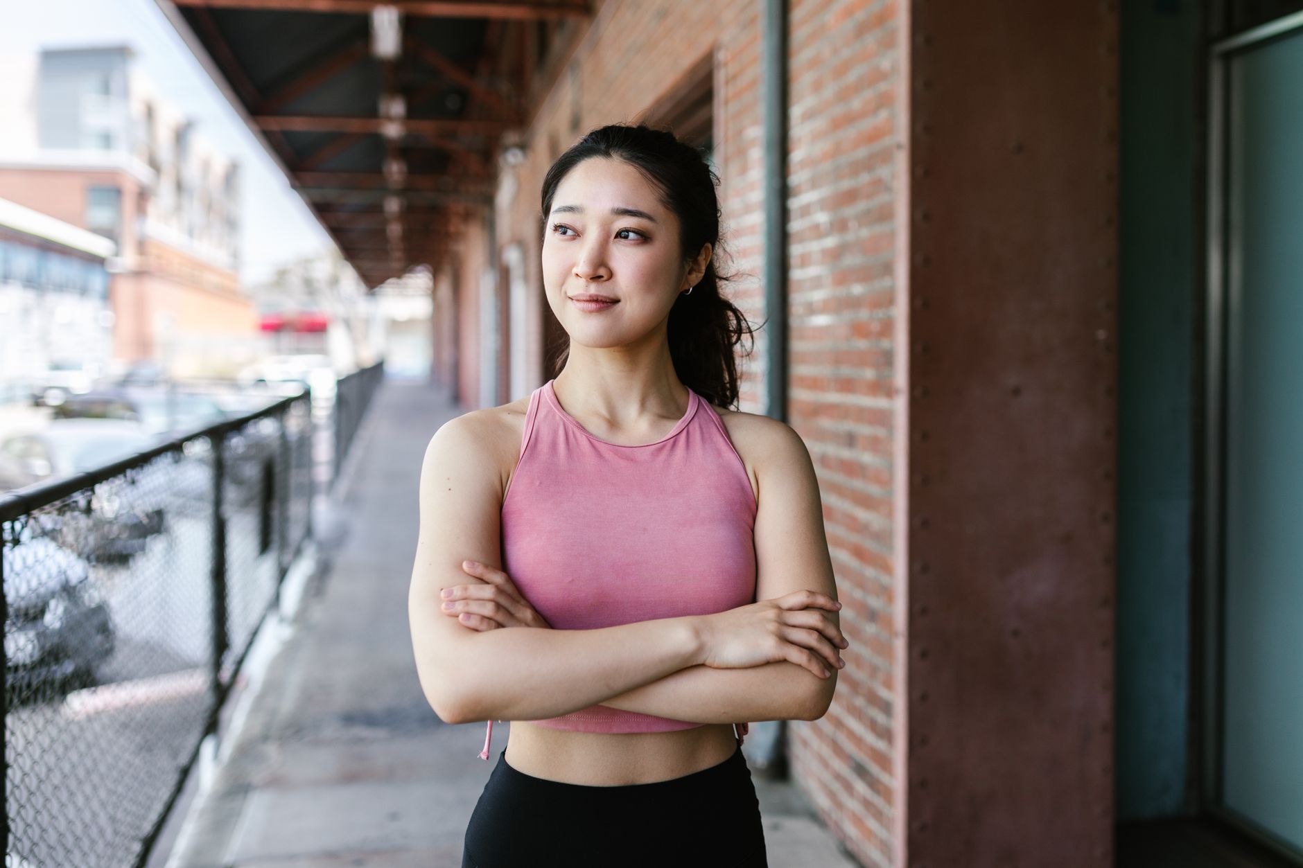 Young woman in activewear stands confidently outdoors, embodying fitness and empowerment.