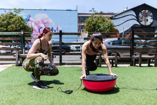 Two women exercising with a balance board outdoors. Fitness and teamwork in action.