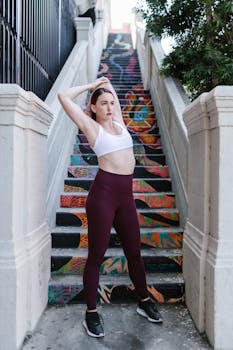 Woman stretching on vibrant graffiti-adorned stairs in outdoor setting for fitness motivation.
