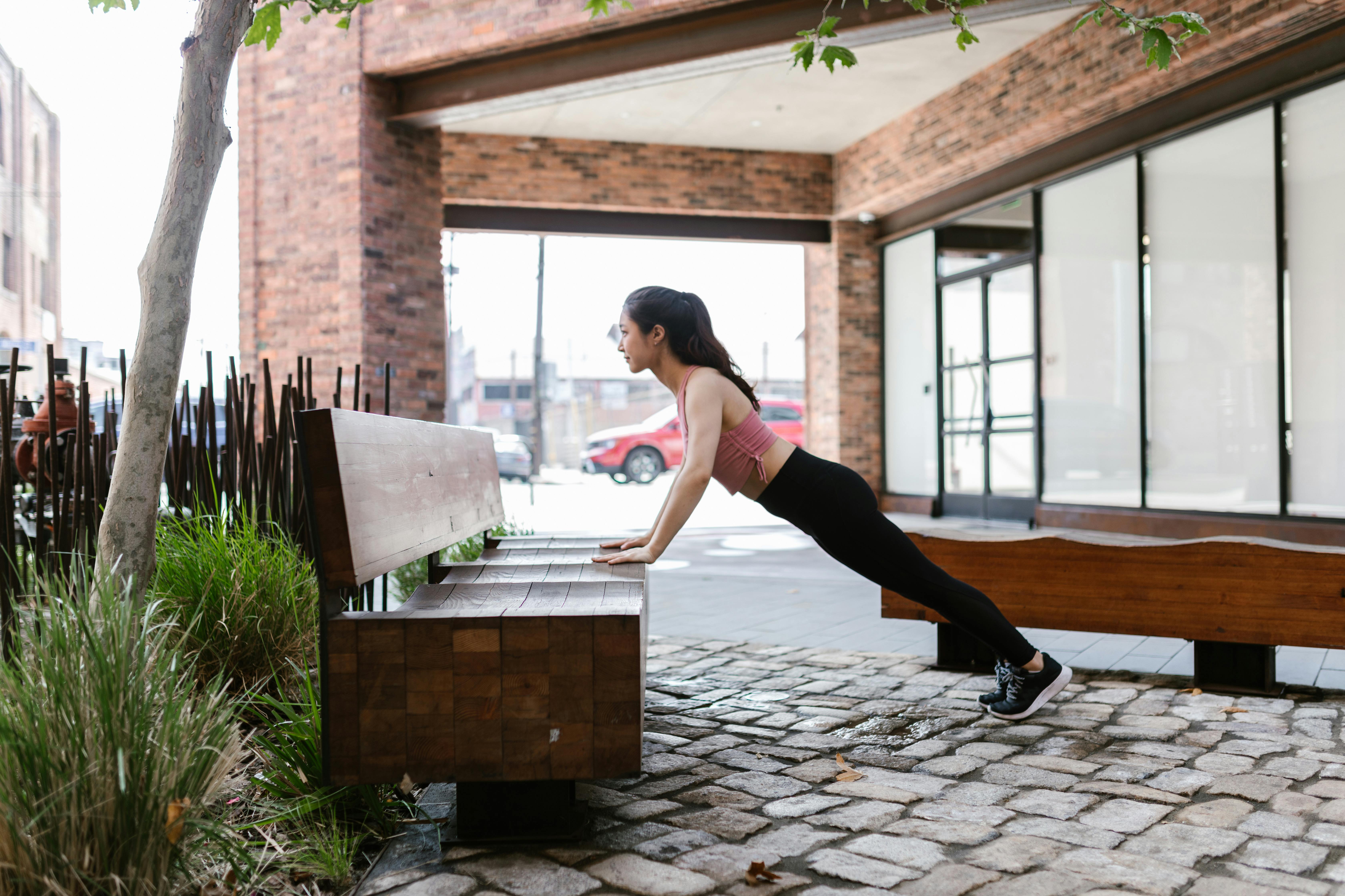 Woman Doing Push Ups on Wooden Bench
