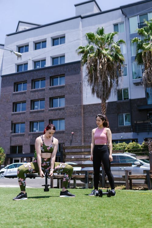 Free Two women performing a fitness workout with dumbbells in an urban setting outdoors. Stock Photo