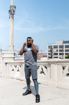 A fit man practices shadow boxing outdoors on a sunny city rooftop, showcasing energy and fitness.
