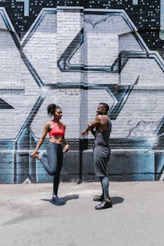 Active couple stretching together against a graffiti wall, emphasizing fitness and connection.