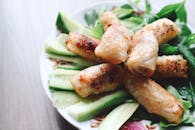 盘子里放着脆皮春卷，配着新鲜黄瓜和香草