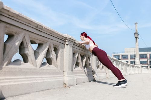 Free Woman performing push-ups on a bridge for outdoor fitness training. Stock Photo