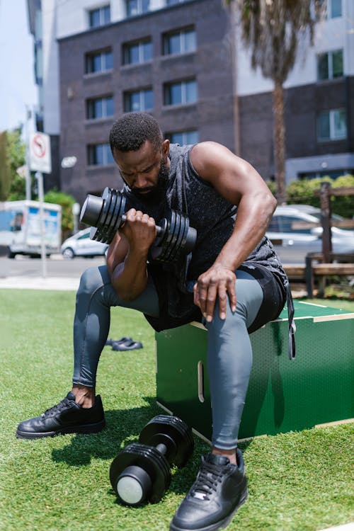 Free Man Sitting While Lifting Dumbbell Stock Photo