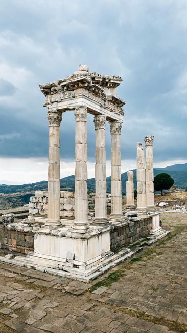 Explore the ancient ruins of the Temple of Trajan in Pergamon, featuring iconic columns under a cloudy sky.