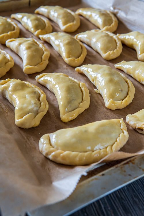 Free A batch of uncooked homemade empanadas arranged on a baking sheet, ready for baking. Stock Photo