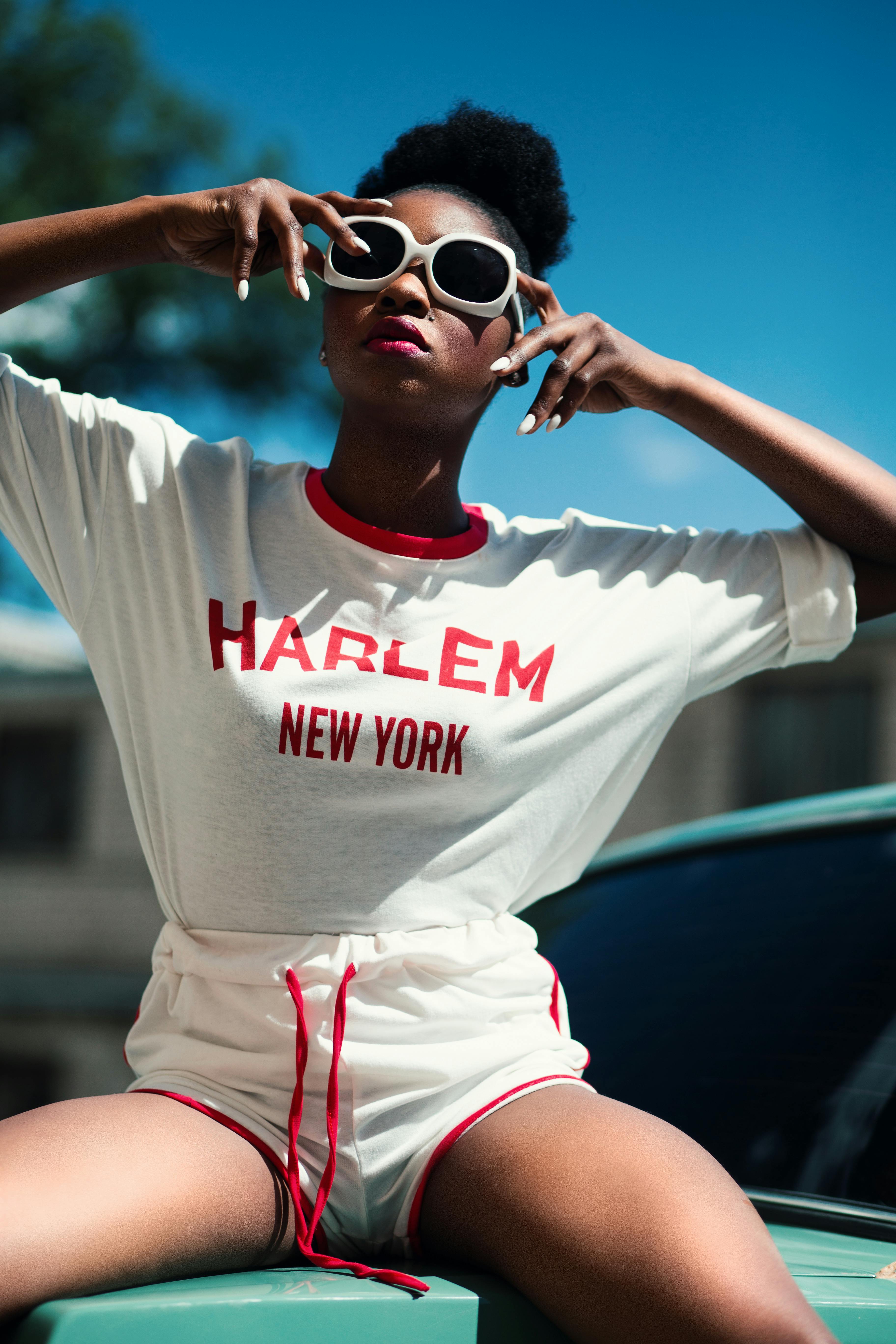 gratis Vrouw Draagt Wit En Rood Harlem New York Shirt Met Ronde Hals, Vleermuismouwen En Dolfijnshort Met Trekkoord Stockfoto