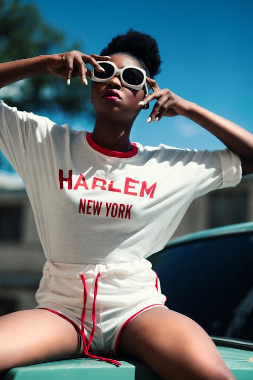 Miễn phí Người Phụ Nữ Mặc áo Sơ Mi Cánh Dơi Cổ Tròn In Màu Trắng Và đỏ Harlem New York Với Quần đùi Cá Heo Dây Rút Ảnh lưu trữ