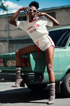 一名穿着纽约哈莱姆区服装的时尚女子白天在一辆老爷车旁摆姿势