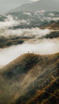 A breathtaking aerial view of clouds enveloping rolling hills, creating a mystical mountain landscape.