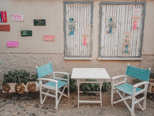 Wooden Folding Chairs and Table Beside Concrete Wall