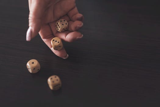 A close-up view of a hand rolling wooden dice on a dark wooden surface, showcasing a classic gaming moment.