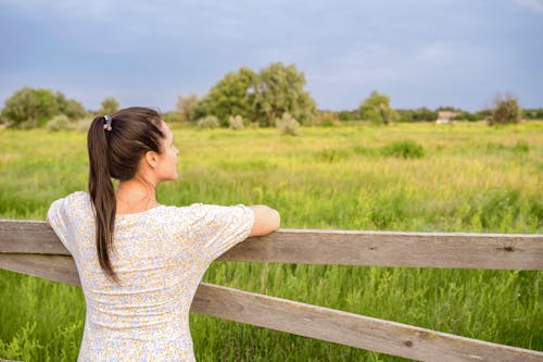 Woman Standing Beside a Wooden Fence