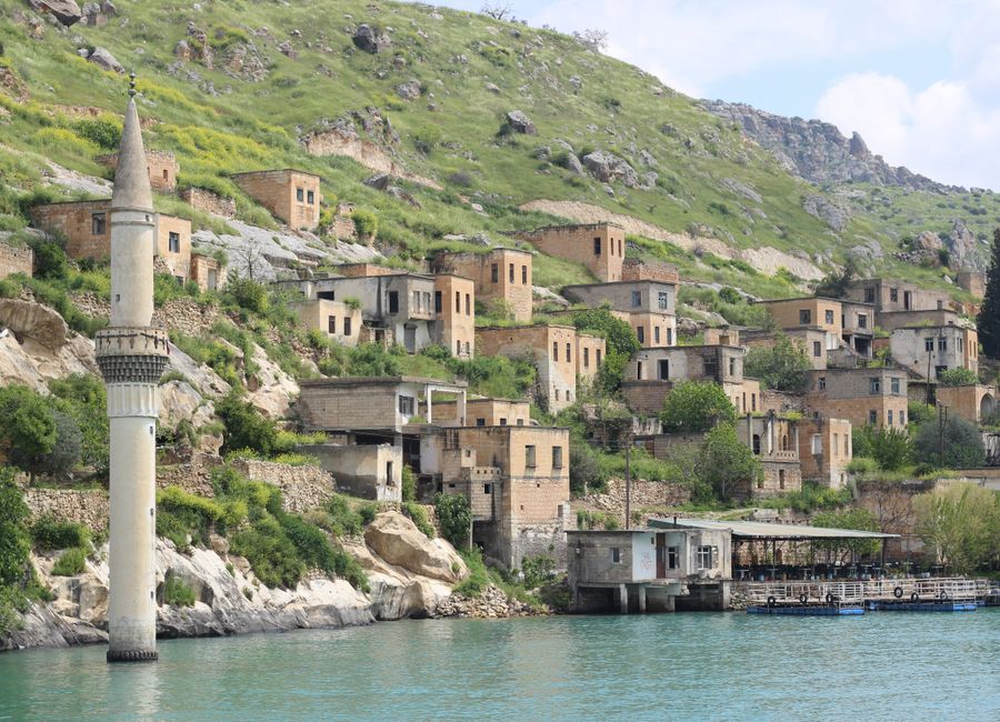Picturesque Halfeti village with stone houses along the river, surrounded by lush hills.